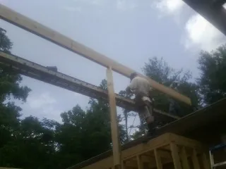 Carpenter setting a ridge beam over a new addition frame — Ice Dam Removal by Roofing Brothers in Gilchrist