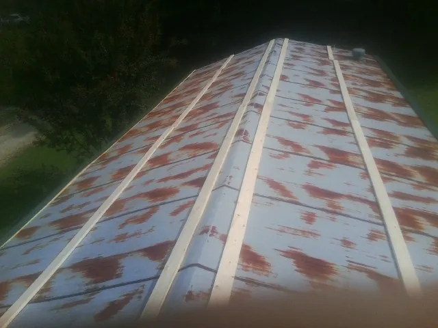 Rusted metal roof panels with new wood purlins before replacement — Storm Damage Roof Repair in Gilchrist by Roofing Brothers
