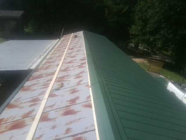 Old rusted panels beside newly installed green metal roofing — Wind Damage Roof Repair by Roofing Brothers in Gilchrist