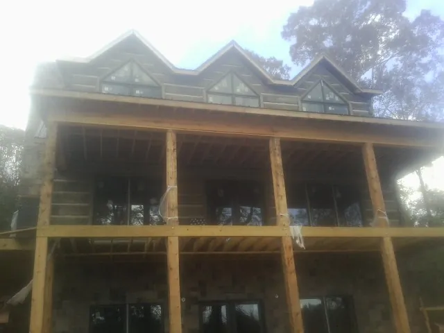 Dormers and porch framing on a large log home under construction — Roof Coating work by our crew in Gilchrist
