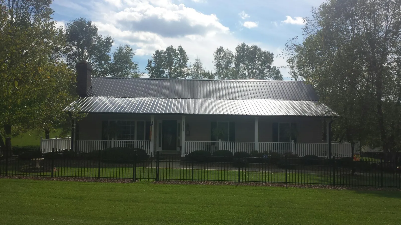 Gray metal roof on a brick ranch with a full width front porch — Gutter Guard Installation work by our crew in Gilchrist